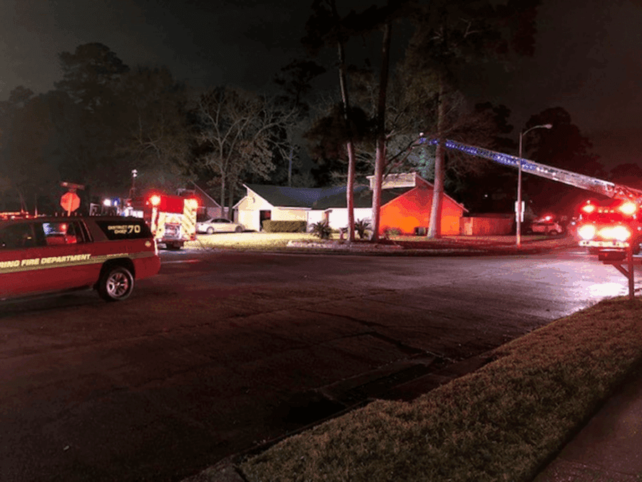 Fire trucks and emergency vehicles with flashing lights are parked outside a house at night, responding to a fire incident.